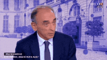 a man in a suit and tie is talking on a television screen
