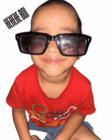 a young boy wearing sunglasses and a red shirt that says cats