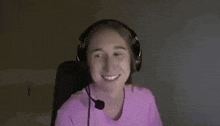 a woman wearing headphones is smiling while sitting in front of a computer screen .