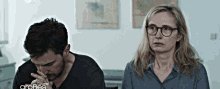 a man and a woman are sitting next to each other and the woman has glasses