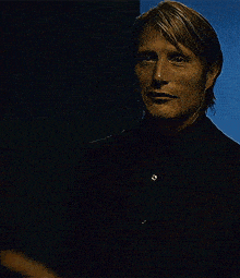 a man wearing a black suit and black shirt is looking at the camera