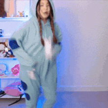 a woman in a blue onesie with a hood is dancing