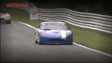 a blue race car is driving down a track with the word autocar on the bottom