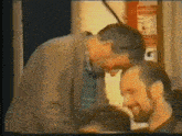 a man with a beard is kissing another man on the forehead in a video .