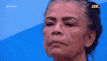 a woman is looking at her face in a mirror with globoplay written on the bottom of the screen