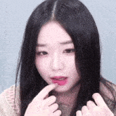 a close up of a woman 's face with long black hair and pink lipstick .