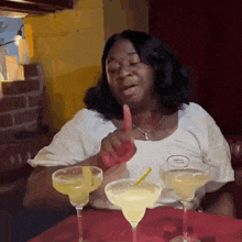 a woman is sitting at a table with three margarita glasses and a name tag that says texas