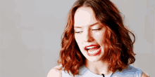 a woman with red hair and red lips is making a funny face with her mouth open .