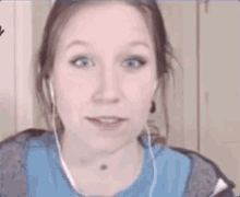 a woman wearing headphones and a blue shirt is smiling and saying yes