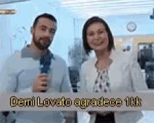 a man and a woman are standing next to each other with a sign that says demi lovato agradece 1kk .