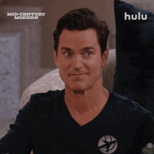 a man in a black shirt is smiling in front of a hulu logo