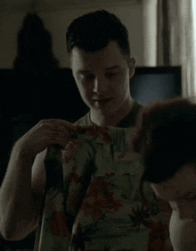 a man is holding a floral shirt over a woman 's head in a dark room .