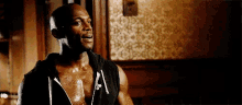 a man is standing in a dark room wearing a black hoodie without a shirt on .