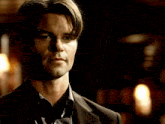 a man in a suit stands in a dark room looking at something