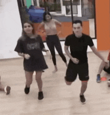 a group of people are dancing in a gym while a man is running .