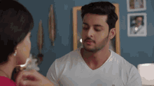 a man in a white shirt is talking to a woman in a room