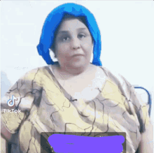 a woman with a blue head scarf on her head is sitting in a chair .
