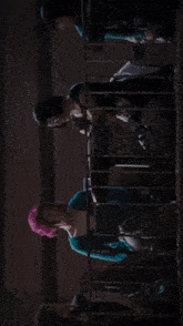 a man and a woman are looking at each other in a dark room with a red exit sign in the background