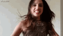 a woman is dancing with her hair in the air and smiling at the camera .