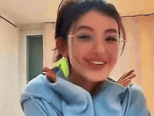 a woman wearing glasses and a blue jacket is smiling and has the name njafaerie on the bottom right