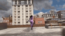 a woman in a purple outfit is running on a rooftop in front of a tall building