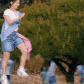 a woman in a white shirt and blue shorts is jumping in the air ..