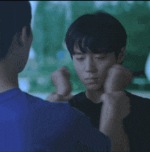 a man in a blue shirt holds another man 's face in his hands