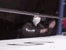 a person wearing a face mask is sitting in a boxing ring