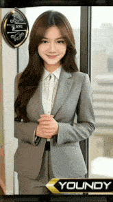 a woman in a suit is standing in front of a window with the name youndy on the bottom
