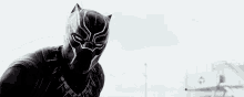 a black panther is wearing a helmet and standing in front of a white building .