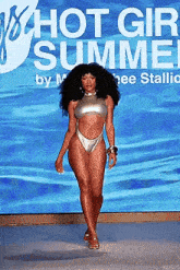 a woman in a silver bikini is walking down a runway at a fashion show .
