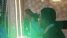 a man and a woman are standing next to each other in a room with green lights behind them .