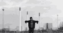 a black and white photo of a man standing in front of a large explosion .