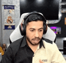 a man wearing headphones is sitting in a chair and giving a thumbs up .