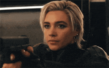 a woman with blonde hair is holding a black gun