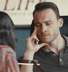 a man with a beard is sitting in front of a woman with his hand on his chin