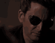 a close up of a man wearing sunglasses looking at the camera