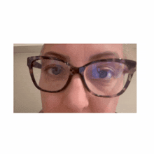 a woman wearing glasses looks at the camera with her eyes closed