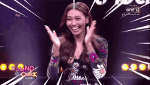 a woman in a floral dress applauds in front of a one 31 sign