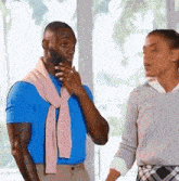 a man in a blue shirt with a pink scarf around his neck is talking to a woman .
