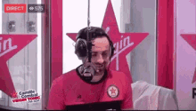 a man wearing headphones is talking into a microphone in front of a virgin sign