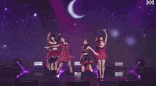 a group of girls are dancing on a stage with a purple background .