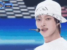 a man wearing a white hat and ear buds stands in front of a screen that says comeback 8 team on it
