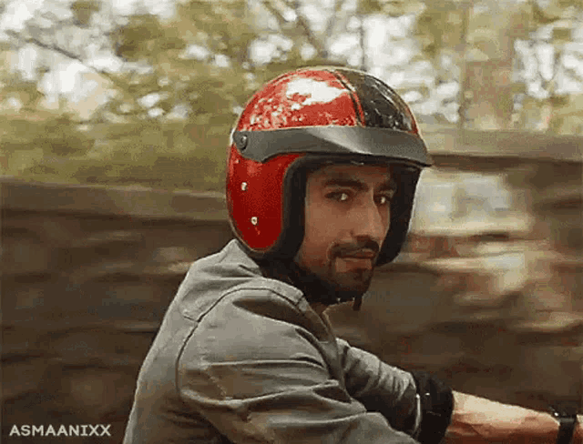 a man wearing a red helmet is sitting on a motorcycle .