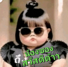 a baby wearing sunglasses has a bun on her head and says ' a ' on the bottom right