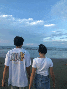 a man and a woman are standing on a beach and the man is wearing a hoop shirt