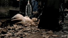 a woman in a white dress is laying on the floor with leaves on the floor