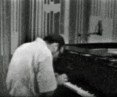 a man in a white shirt is playing a piano in a black and white photo