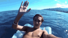 a shirtless man floats on a raft in the ocean