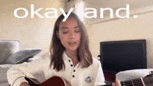 a girl singing and playing a guitar with the words okay and written above her